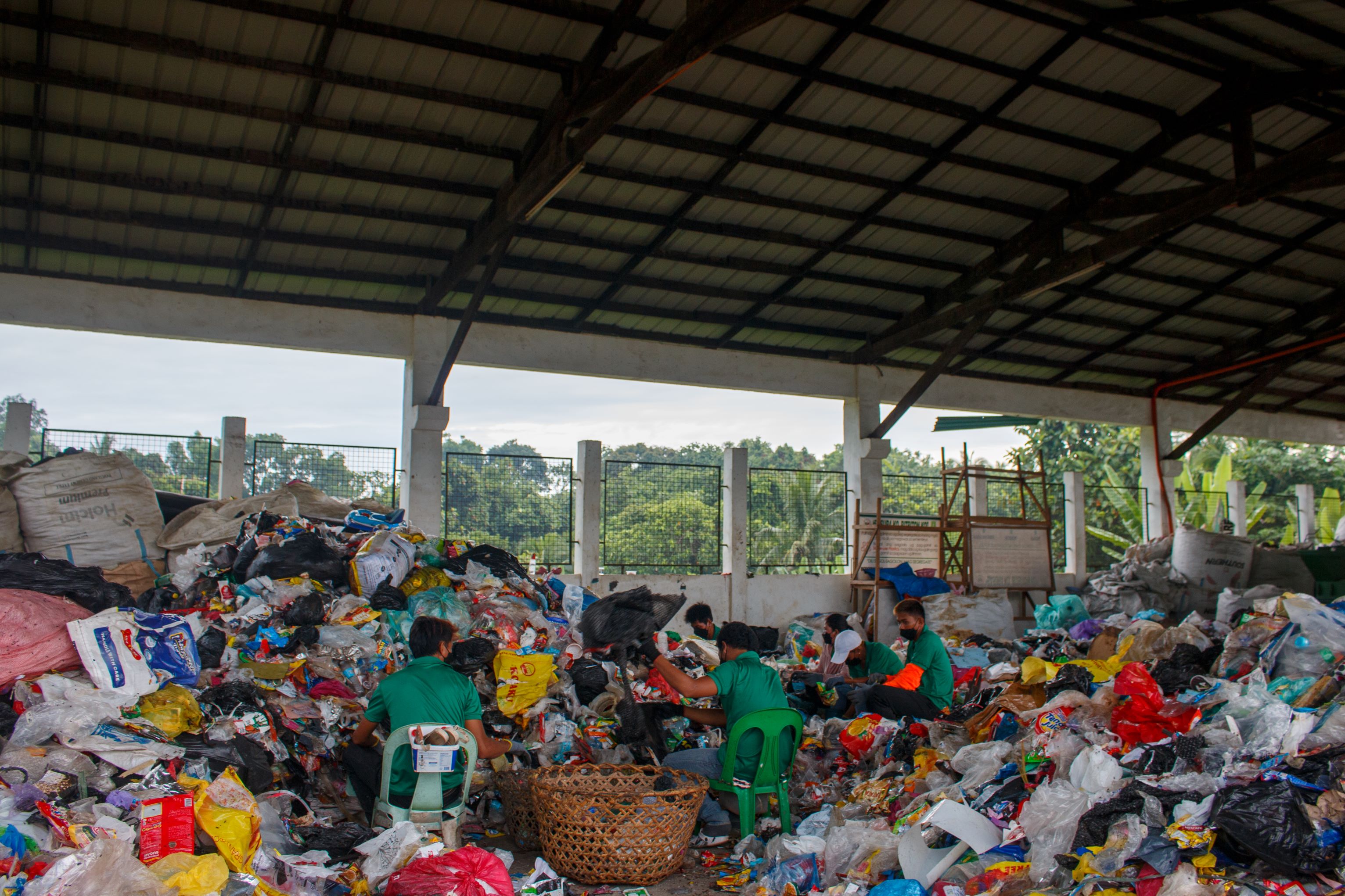 Waste workers sort plastics at the city’s Residual Containment Area .